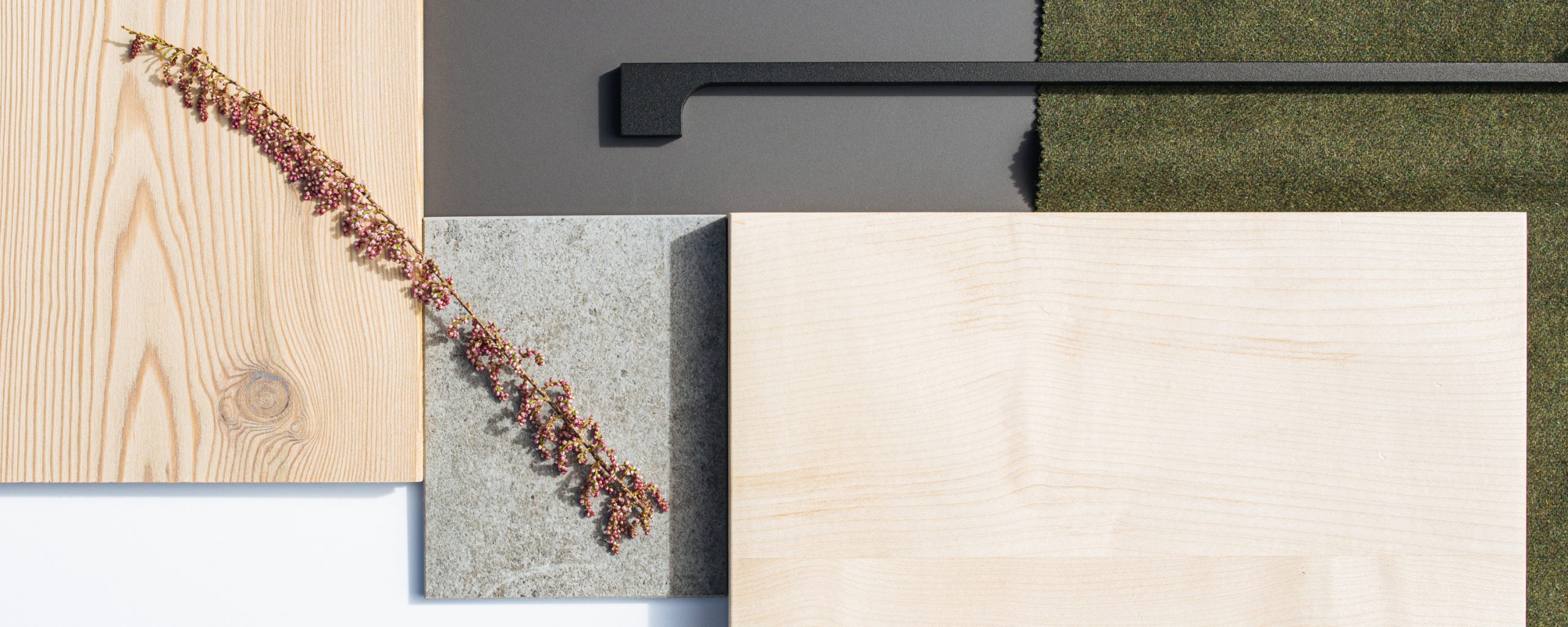 Ausgesuchte Materialien für die Innenarchitektur: Holzplatten, Steinplatten, schwarzer, schmaler Küchengriff, grünes Textil
